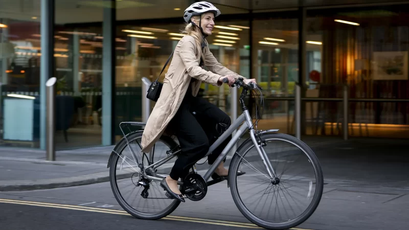 mujer sonriendo andando en bicicleta por la ciudad con casco