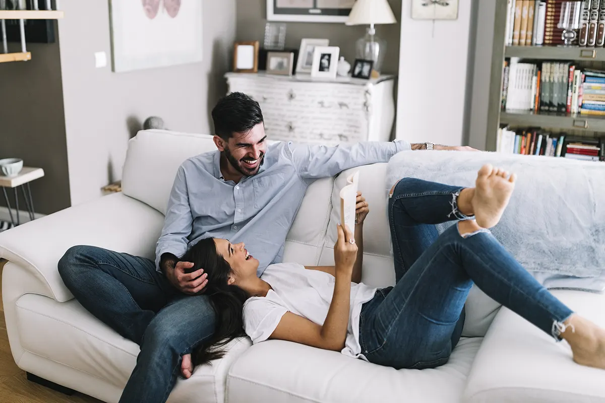 joven pareja feliz sonriendo sentados en el sillón