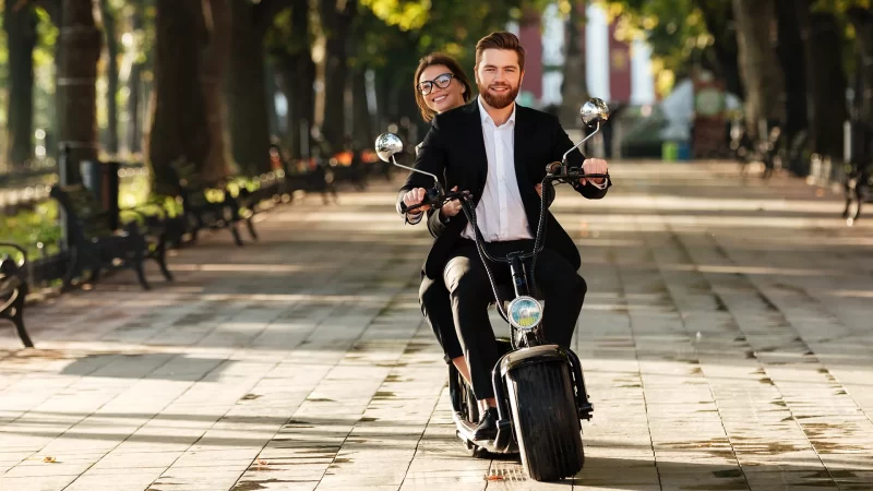 hombre y mujer jóvenes en una scooter eléctrica en una plaza