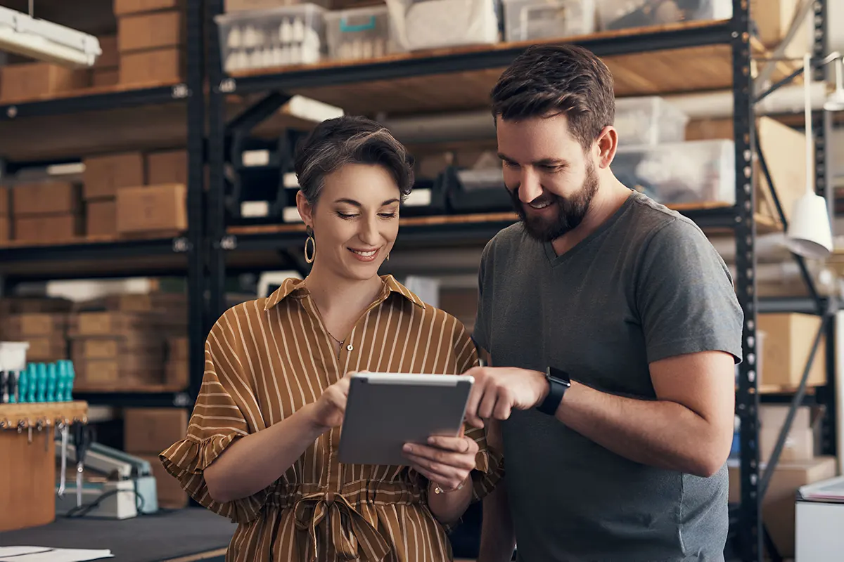 hombre y mujer sonriendo revisando el inventario en un depósito