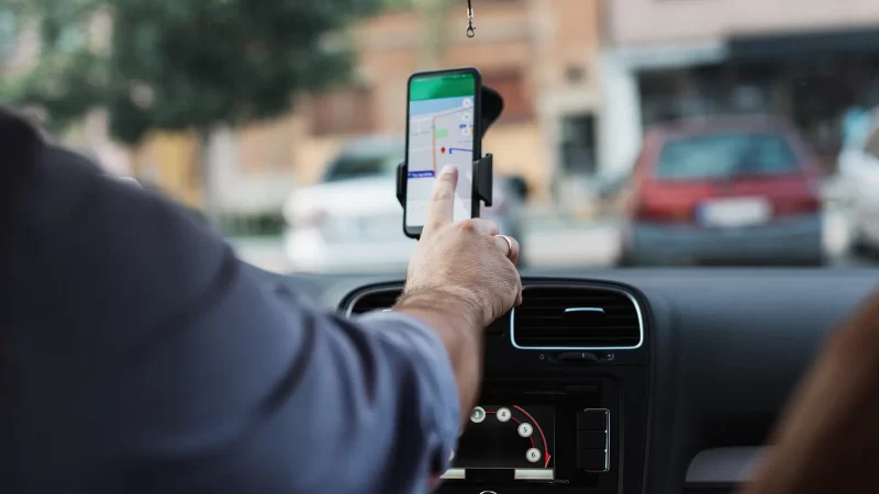 hombre navegando en app de mapa en celular dentro de un auto
