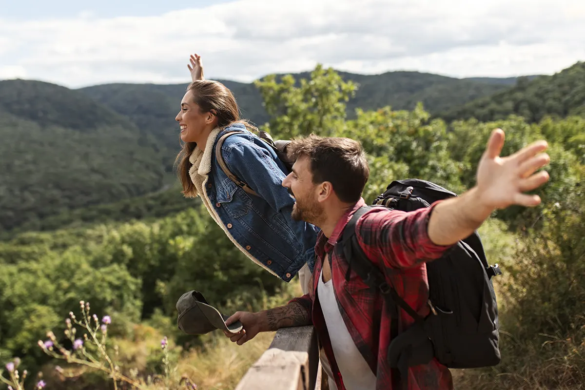 hombre y mujer felices sonriendo mirando la naturaleza desde lo alto de un cerro