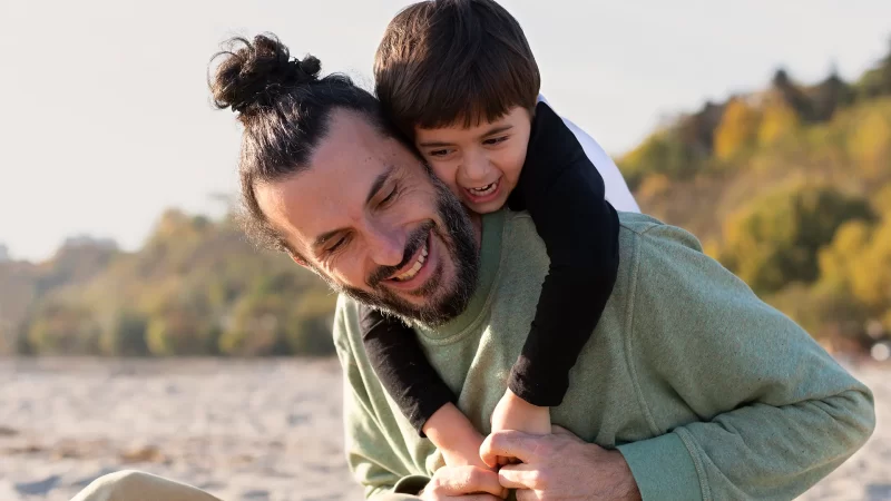 padre e hijo abrazados en la playa sonriendo